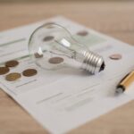 Glödlampa, penna och elavtal på ett bord