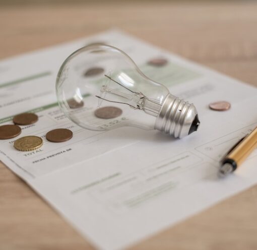 Glödlampa, penna och elavtal på ett bord