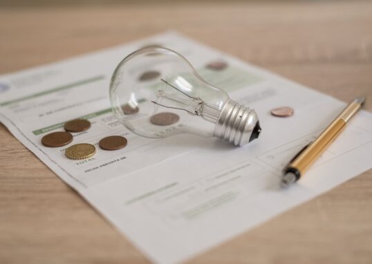 Glödlampa, penna och elavtal på ett bord