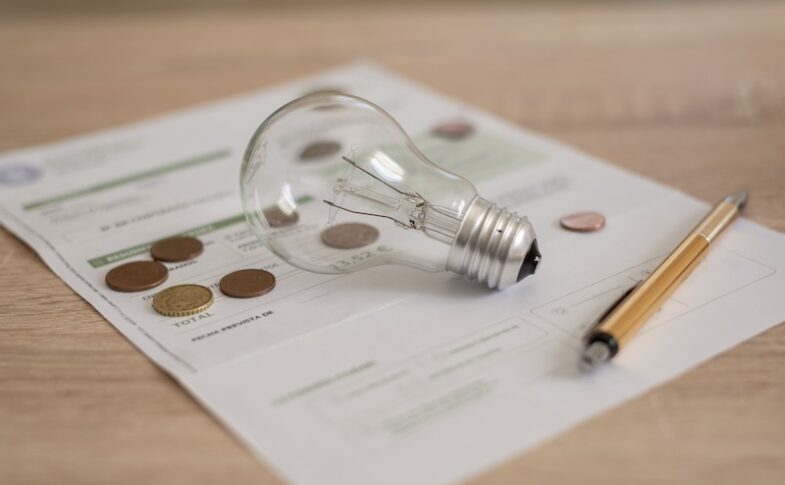 Glödlampa, penna och elavtal på ett bord